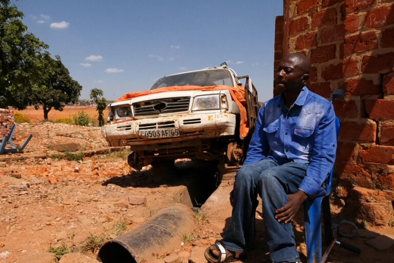 Adéarld Mkonga, a resident who refused to leave and relocate, sits at a mining site. He demanded a “legal relocation” process and better compensation. Image by Eric Cibamba.
