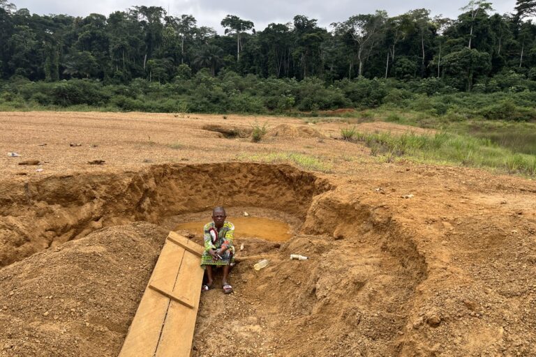 Aristide, the village secretary of Bamegoard, stands dismayed as he looks over what was once a forest. Trees and streams have disappeared, replaced by muddy puddles like the one seen behind him. Image by Elodie Toto for Mongabay.
